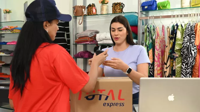 Planejamento de vendas: uma pessoa com roupa da Total Express atende cliente em uma loja.