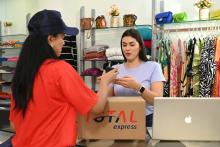 Planejamento de vendas: uma pessoa com roupa da Total Express atende cliente em uma loja.